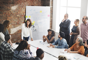 Group of business people around a whiteboard, representing Customer Success Briefings done onsite for companies