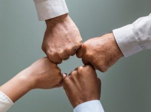 Four closed hands coming together to form a square