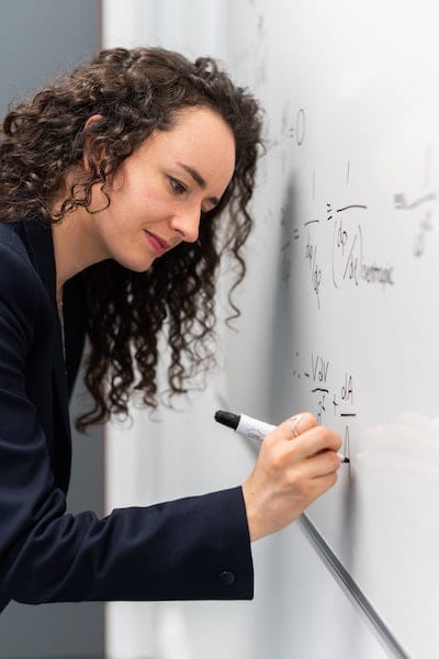 Image of business woman doing math on a whitboard