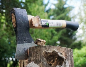 Axe head sunk into wood stump with flying chips