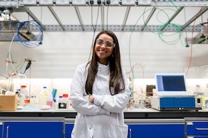 Woman in white coat standing in front of engineering workbench