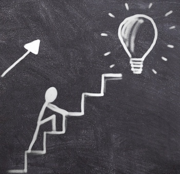 Chalk drawing on blackboard of a man climbing stairs towards a lightbulb